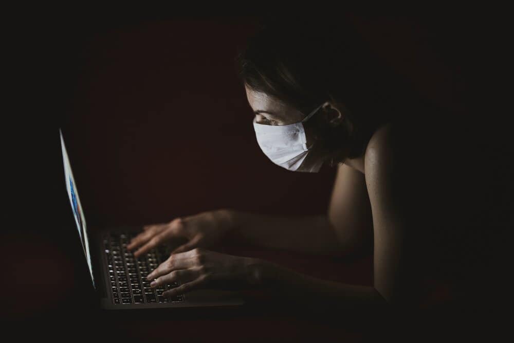woman wearing face mask using macbook pro 4031902