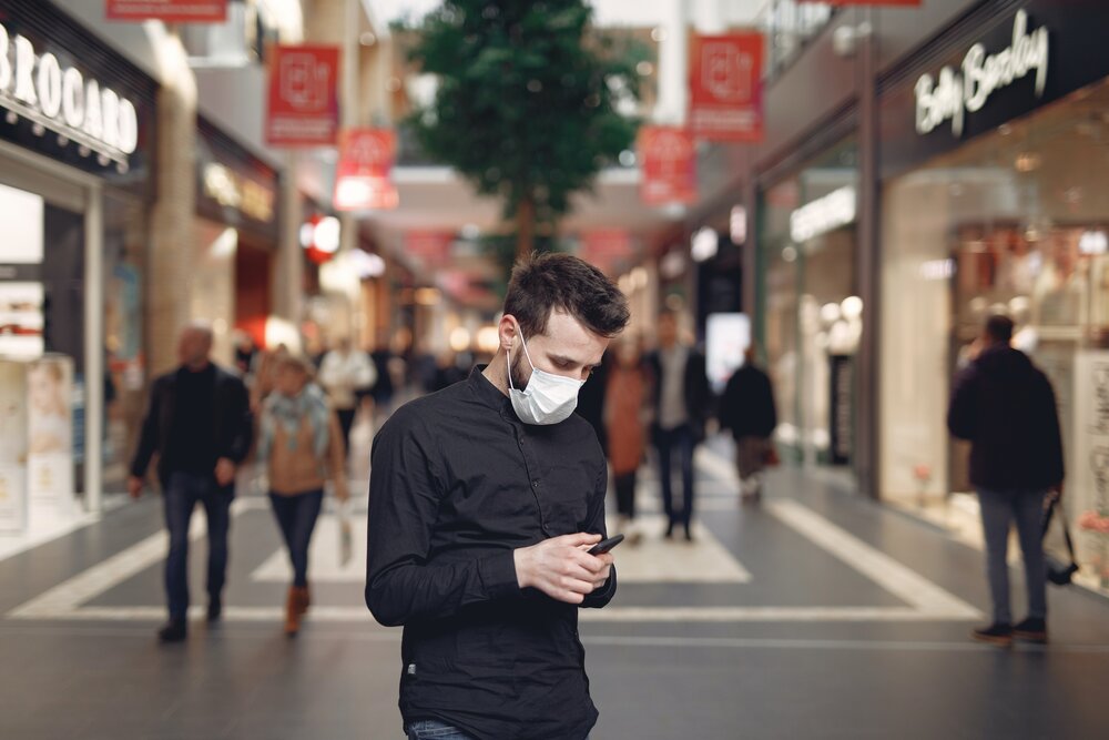 Young man in disposable mask using smartphone in middle of 3983435