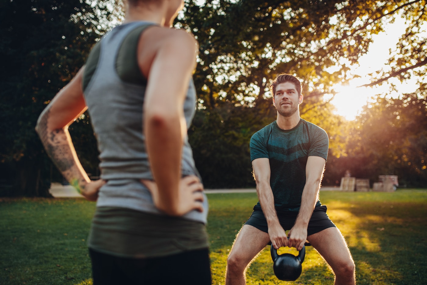 Man works out with kettlebell early morning watched by trainer