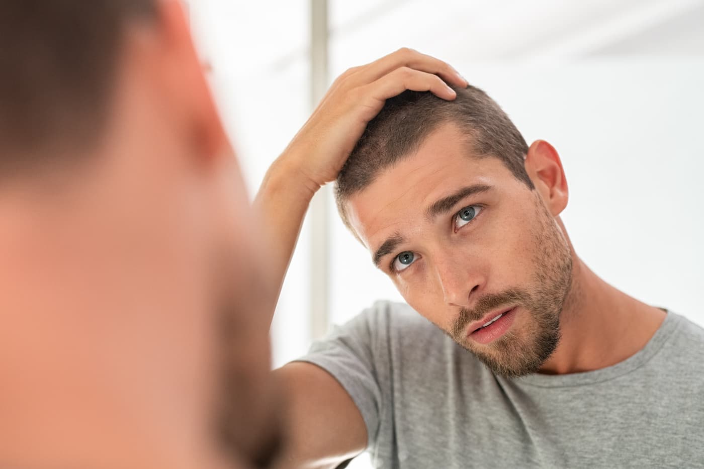 Man checks hair in mirror