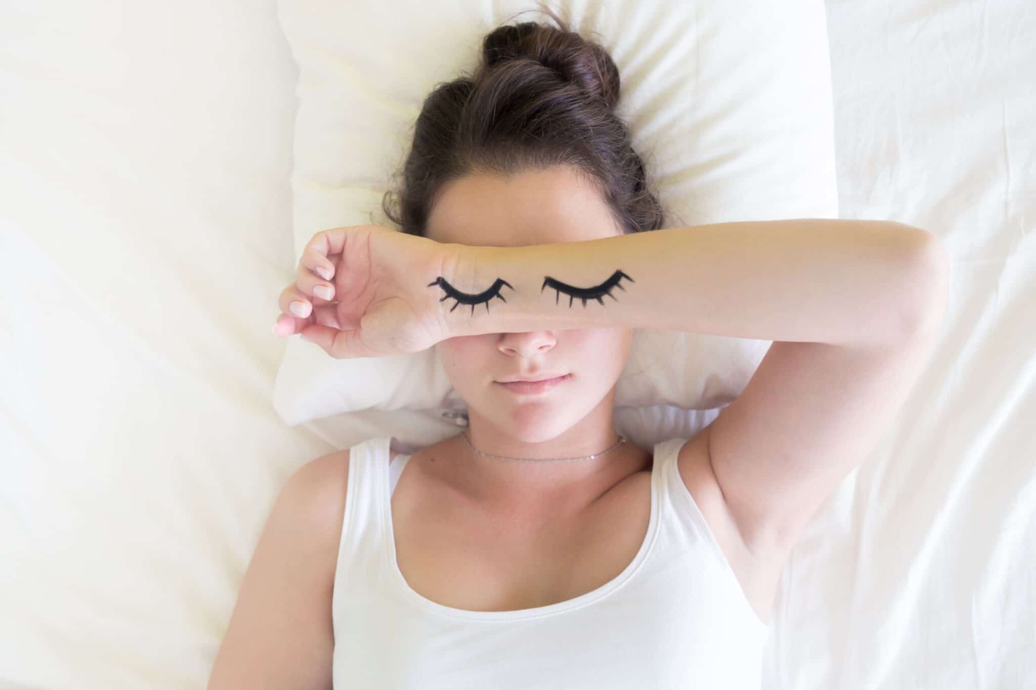 Woman sleeps with eyes drawn on arm