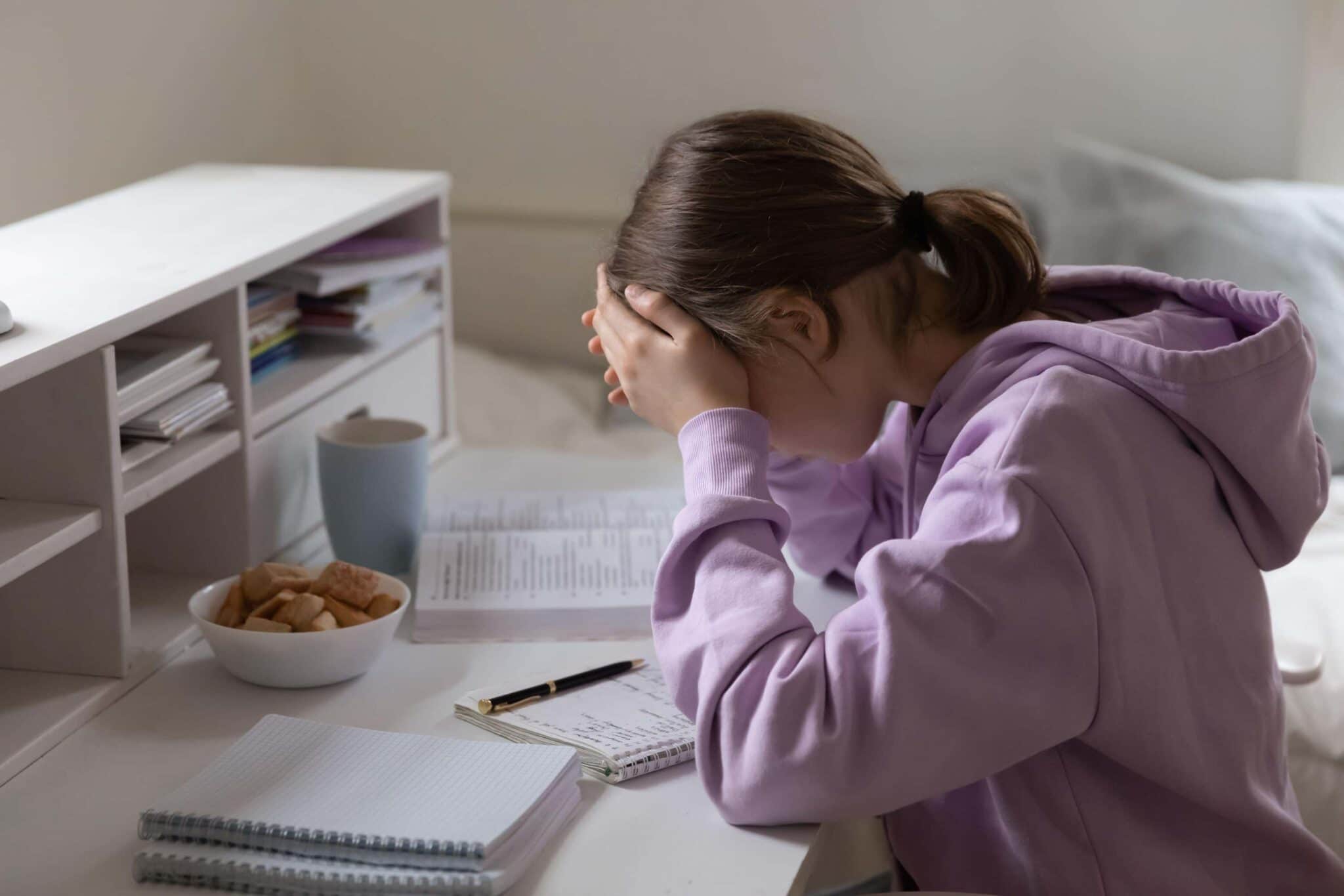 Young girl looks stressed over her desk