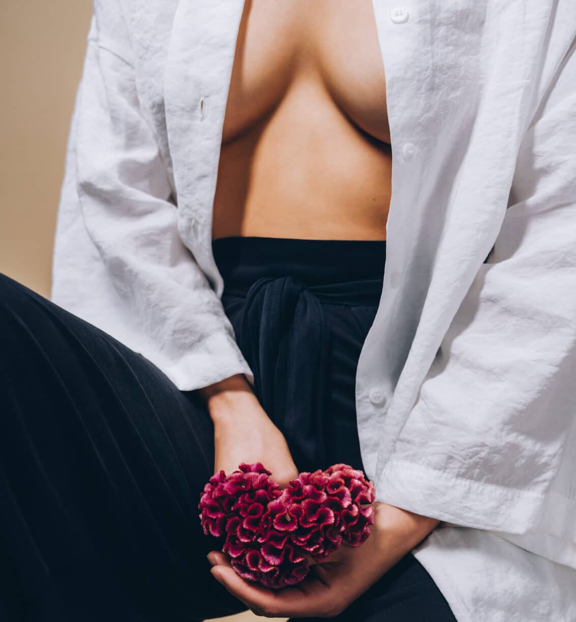 woman with shirt open holds flower