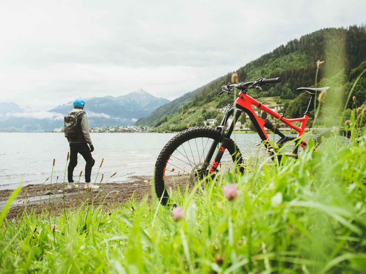 person looks across lake after leaving mountain bike