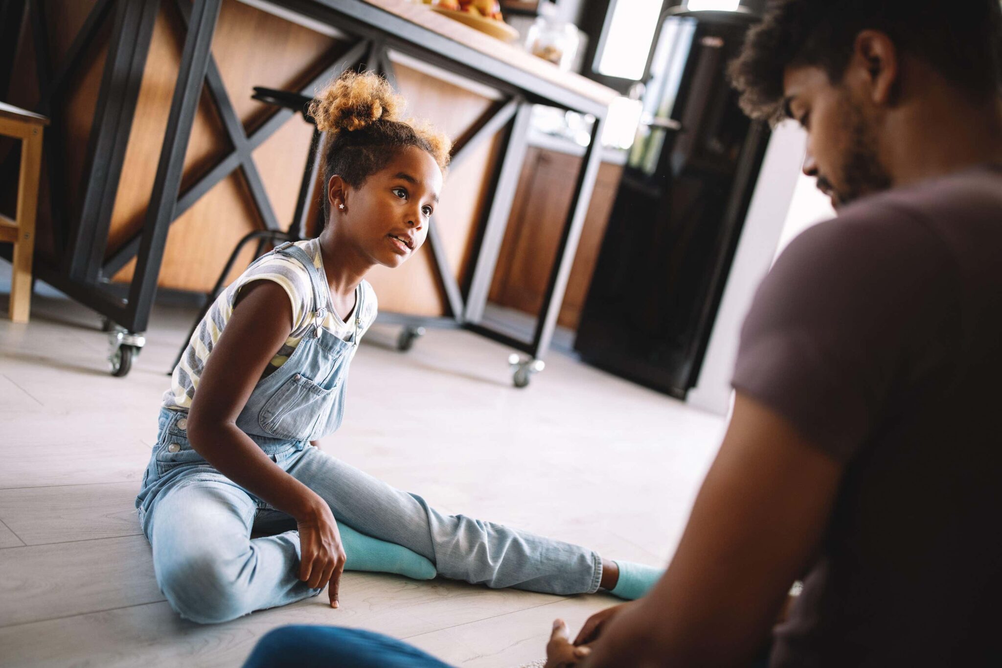 adult talks to child sitting on floor
