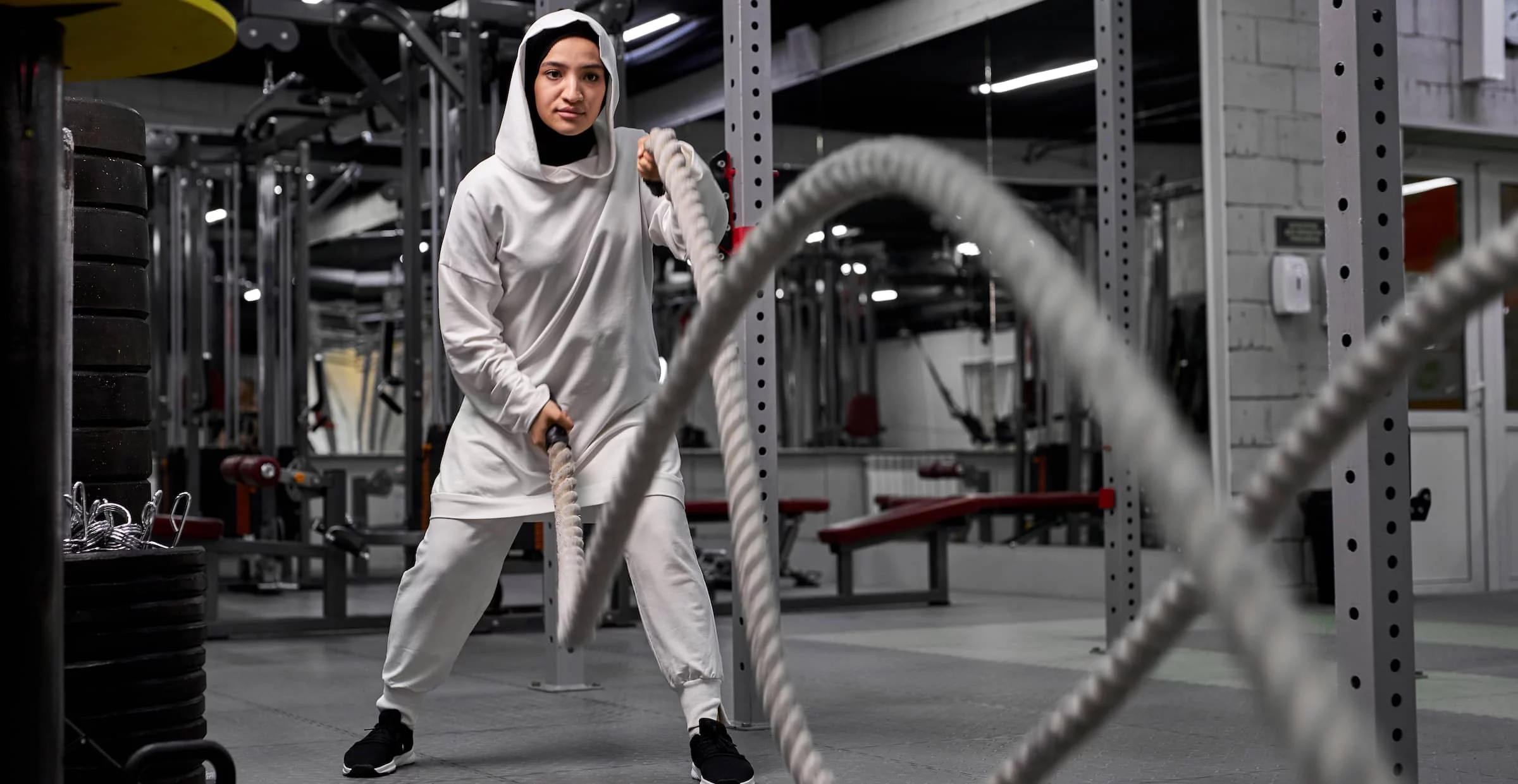 muslim athletic woman working out with ropes at cross fit gym