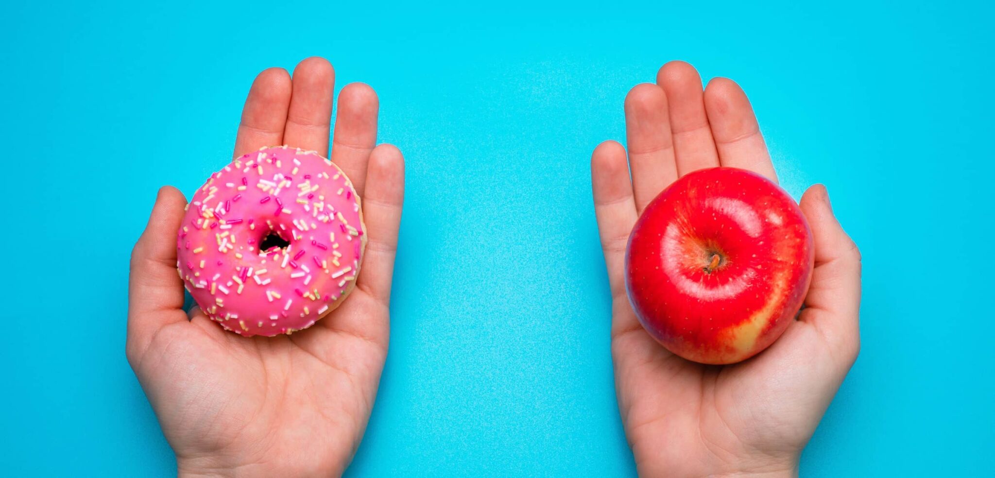 A pair of hands hold donut and apple in each