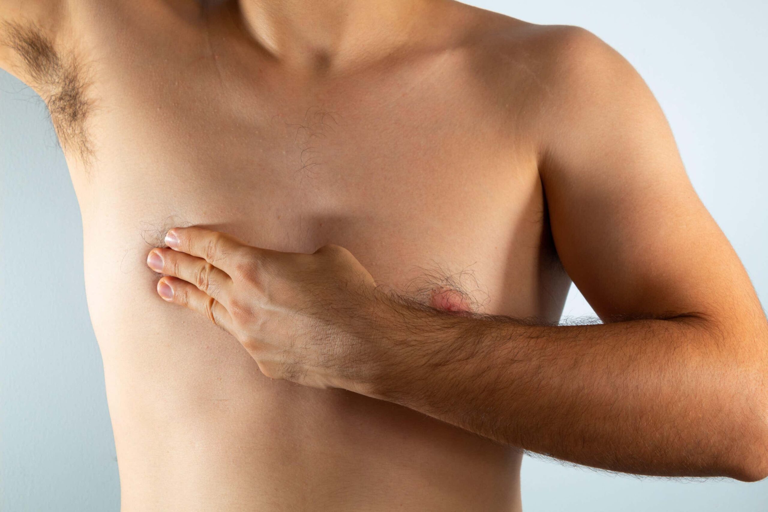 bare chested man feels his chest for lumps scaled