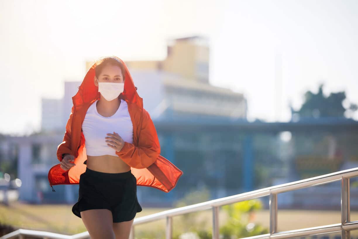Young fitness sport woman running and she wears a mask for protective