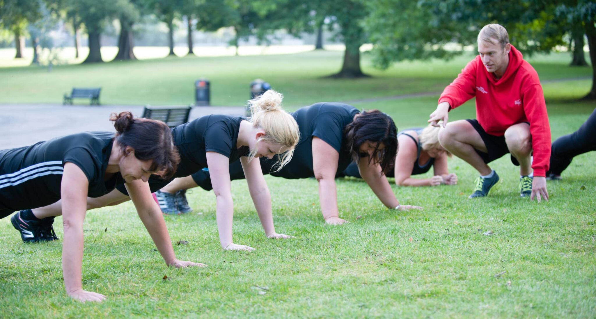 people hold plank position outside in park