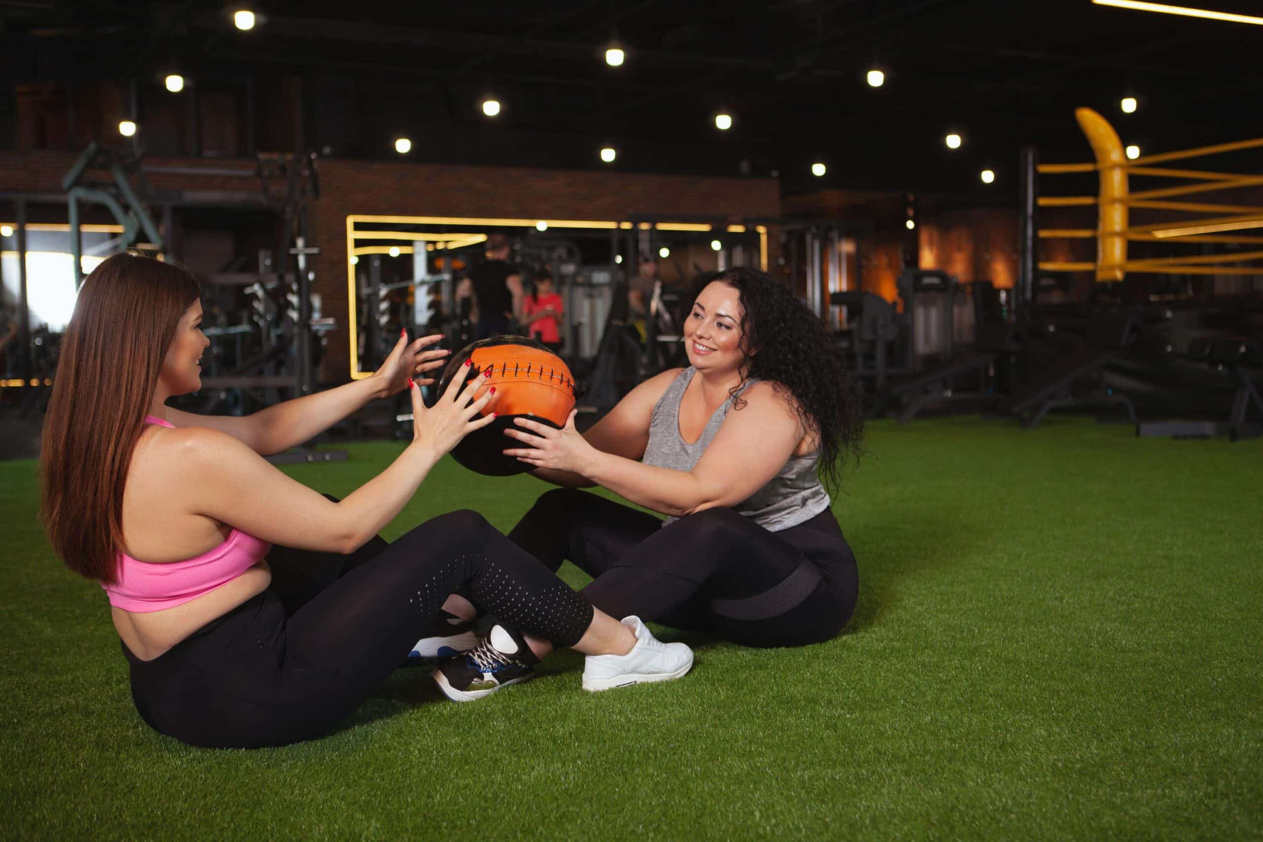 women exercise together in the gym scaled