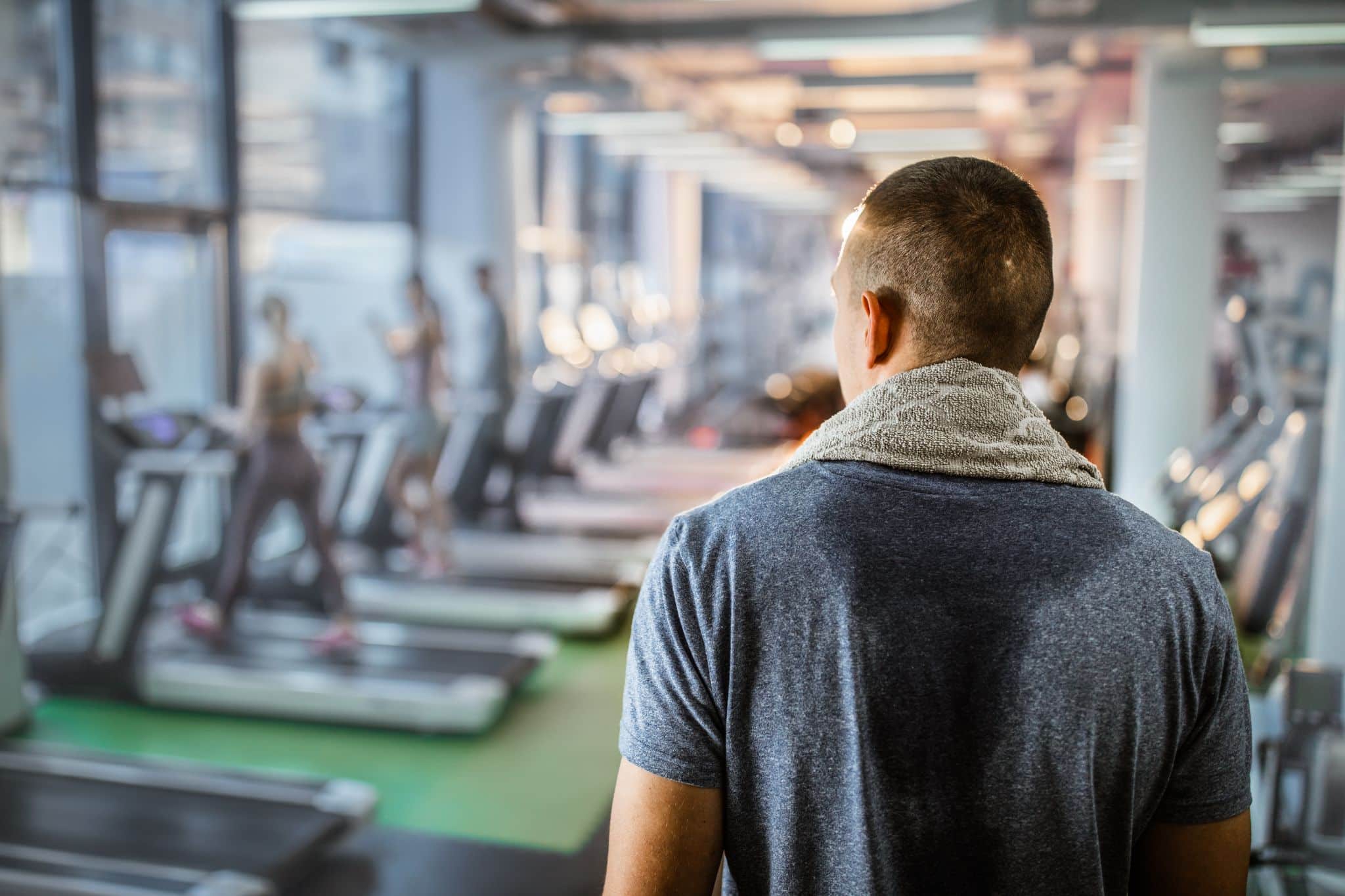 Man in gym with sweat on back of t-shirt