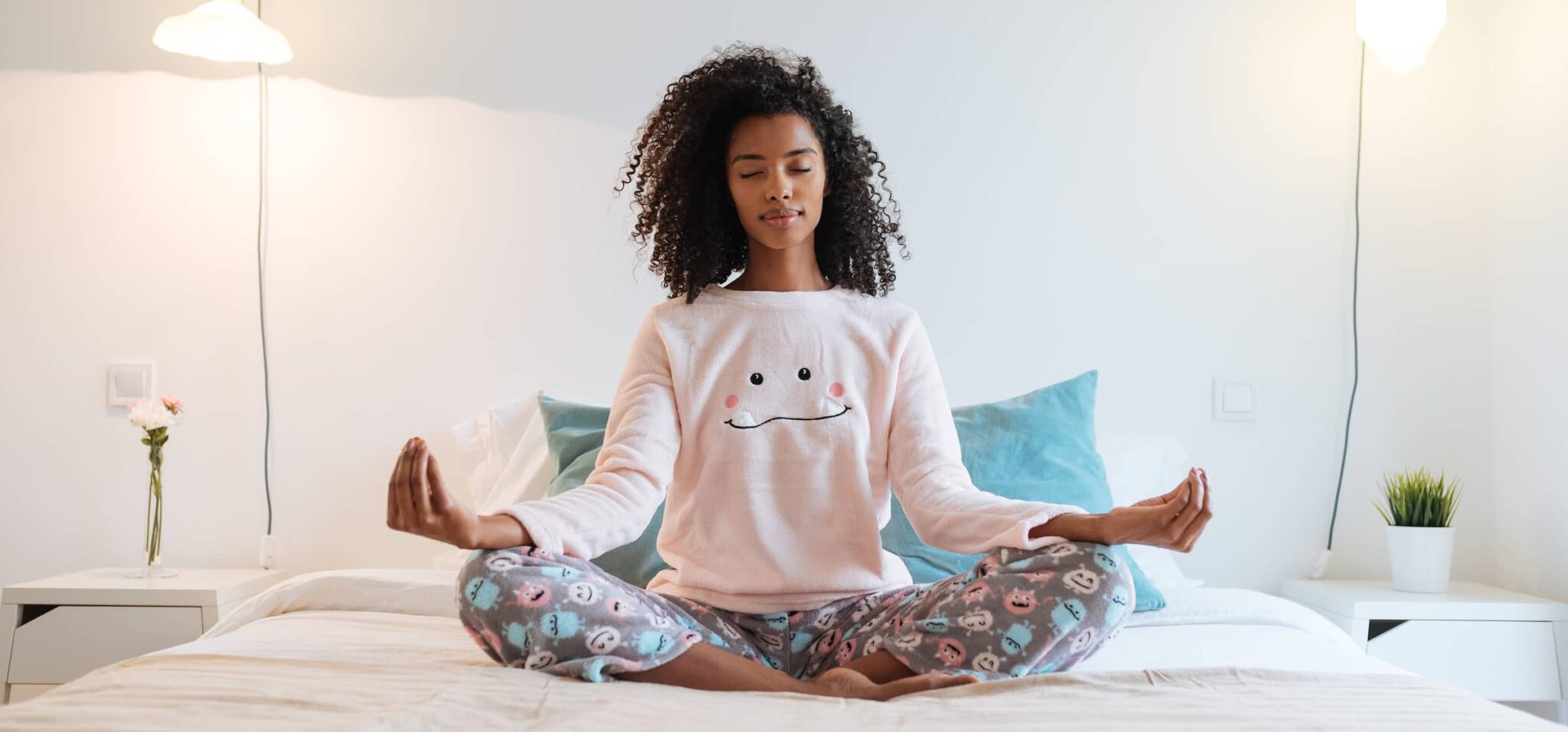 Young black woman relaxed at home doing morning meditation in bed